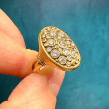 Load image into Gallery viewer, Gold ring with diamond accents held between fingers against a blue background