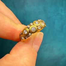 Load image into Gallery viewer, Gold ring with diamonds held between fingers against a blue background