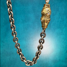 Load image into Gallery viewer, Gold and silver chain necklace with a decorative clasp on a blue background