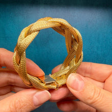 Load image into Gallery viewer, A gold braided mesh bracelet with a lobster clasp, held by two hands against a dark blue textured background.
